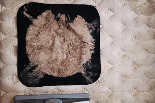 Ausgesaugter Matratzenstaub auf schwarzem Tuch neben dem Saugkopf, Aufnahme 1 von 25