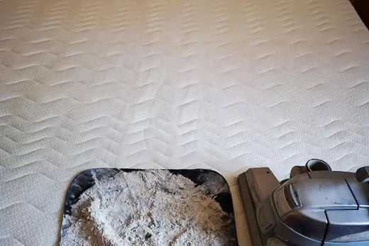 Ausgesaugter Matratzenstaub auf schwarzem Tuch neben dem Saugkopf, Aufnahme 10 von 25