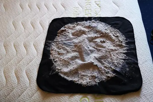 Ausgesaugter Matratzenstaub auf schwarzem Tuch neben dem Saugkopf, Aufnahme 11 von 25