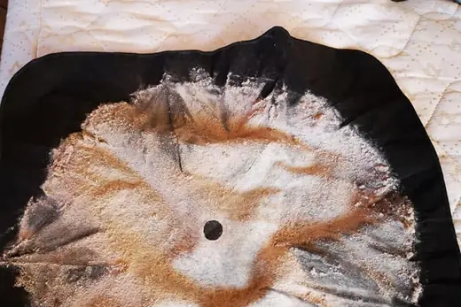 Ausgesaugter Matratzenstaub auf schwarzem Tuch neben dem Saugkopf, Aufnahme 12 von 25
