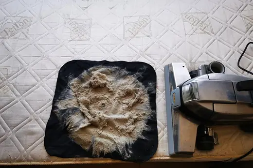 Ausgesaugter Matratzenstaub auf schwarzem Tuch neben dem Saugkopf, Aufnahme 16 von 25
