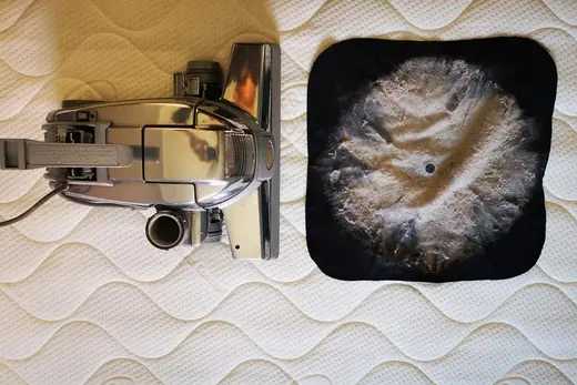 Ausgesaugter Matratzenstaub auf schwarzem Tuch neben dem Saugkopf, Aufnahme 22 von 25