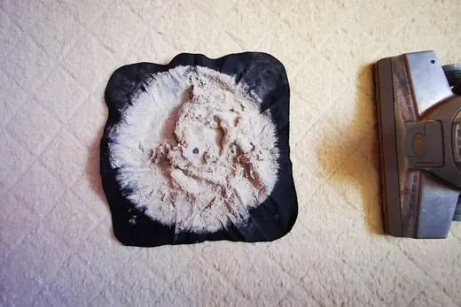 Ausgesaugter Matratzenstaub auf schwarzem Tuch neben dem Saugkopf, Aufnahme 6 von 25