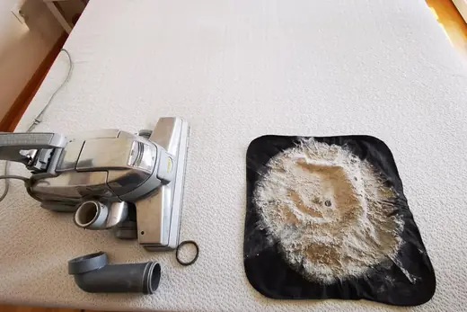 Ausgesaugter Matratzenstaub auf schwarzem Tuch neben dem Saugkopf, Aufnahme 7 von 25