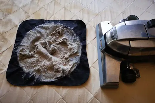 Ausgesaugter Matratzenstaub auf schwarzem Tuch neben dem Saugkopf, Aufnahme 8 von 25